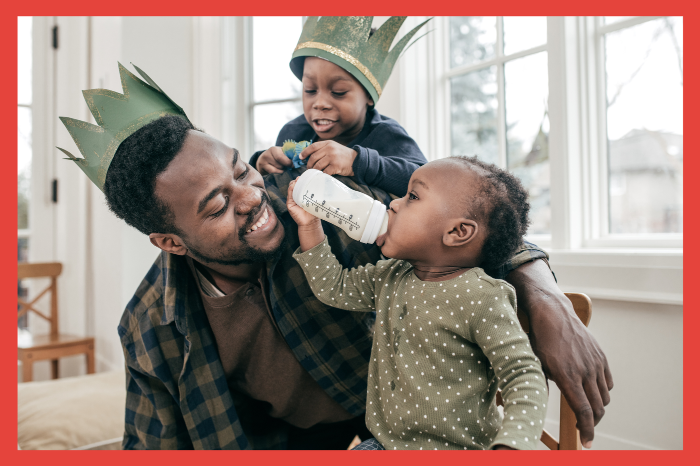 Black father and his two children. One baby and one toddler. Wearing crowns. Smiling and happy. 